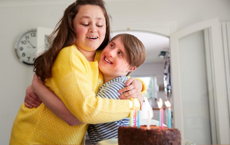 Young Downs Syndrome Couple Celebrating Birthday At Home With Cake